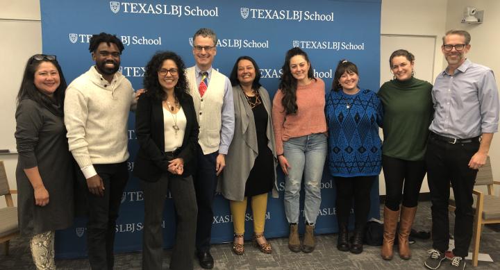 Students, faculty, and guests pose together in front of an LBJ School sign.